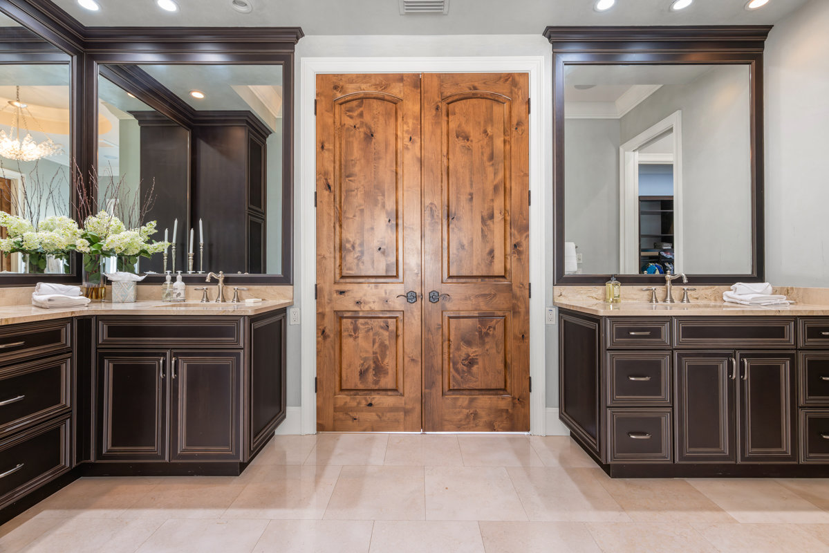 wooden double doors with dark wooden sink cabinets on either side